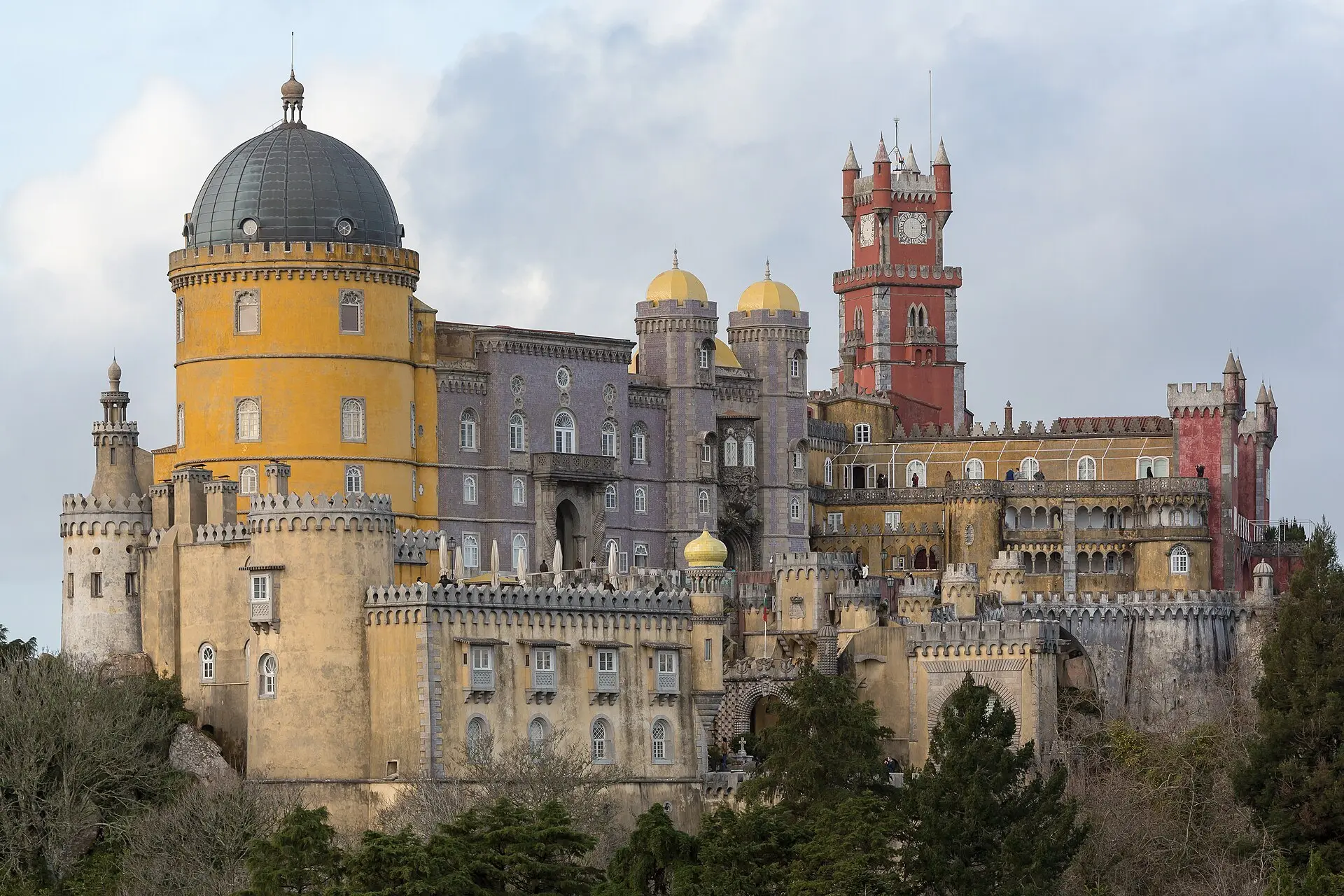 The Pena Palace seen across the trees of Pena Park, with its yellow dome and red clock tower