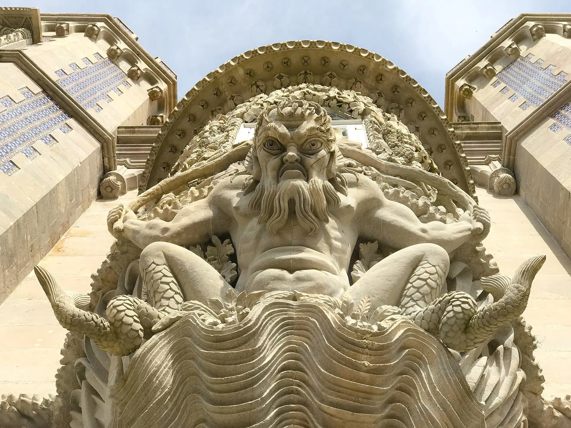 A sea creature carved under a window, holding up the bay above him.