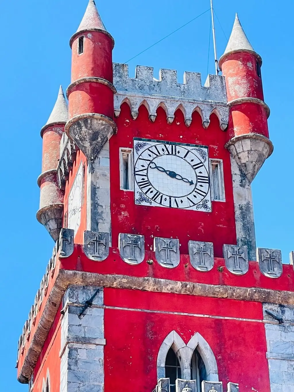 The red clock tower of the Pena Palace against a blue sky