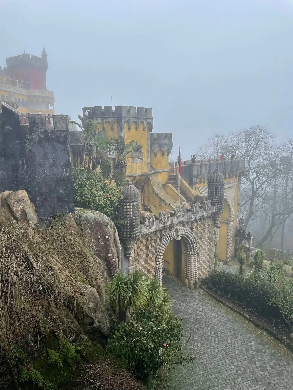 The path to a Pena gateway in thick fog, with yellow walls fading into the mist