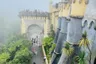 Visitors on the path below the Pena walls in fog