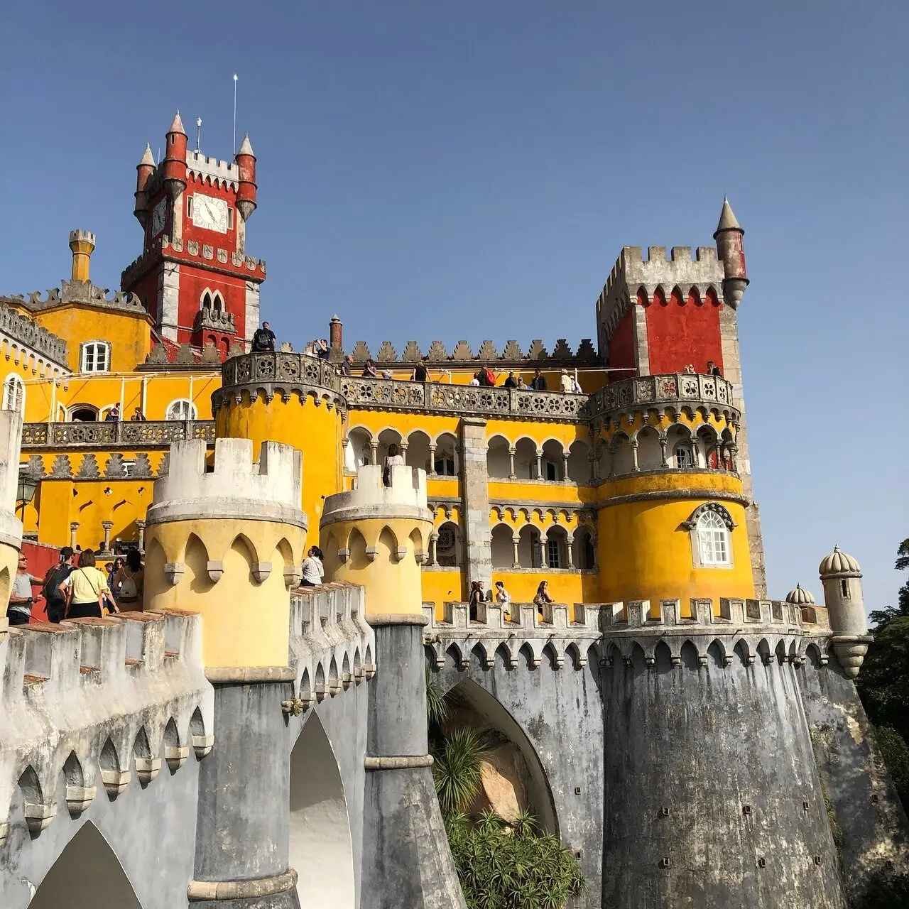 The yellow and red towers of the Pena Palace under a clear sky, photographed by Racho