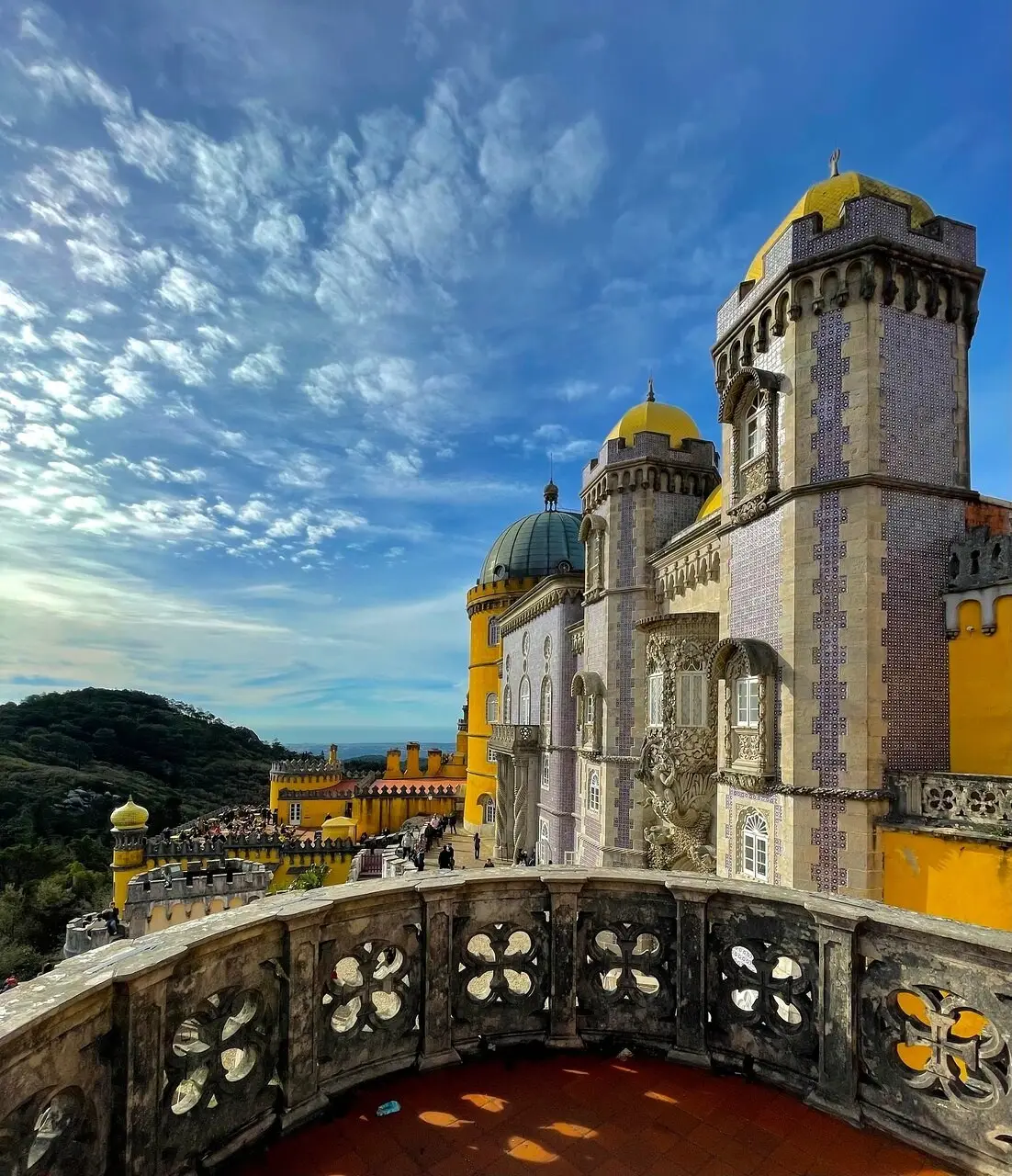 The carved balustrade of a Pena terrace with yellow towers and the forest beyond
