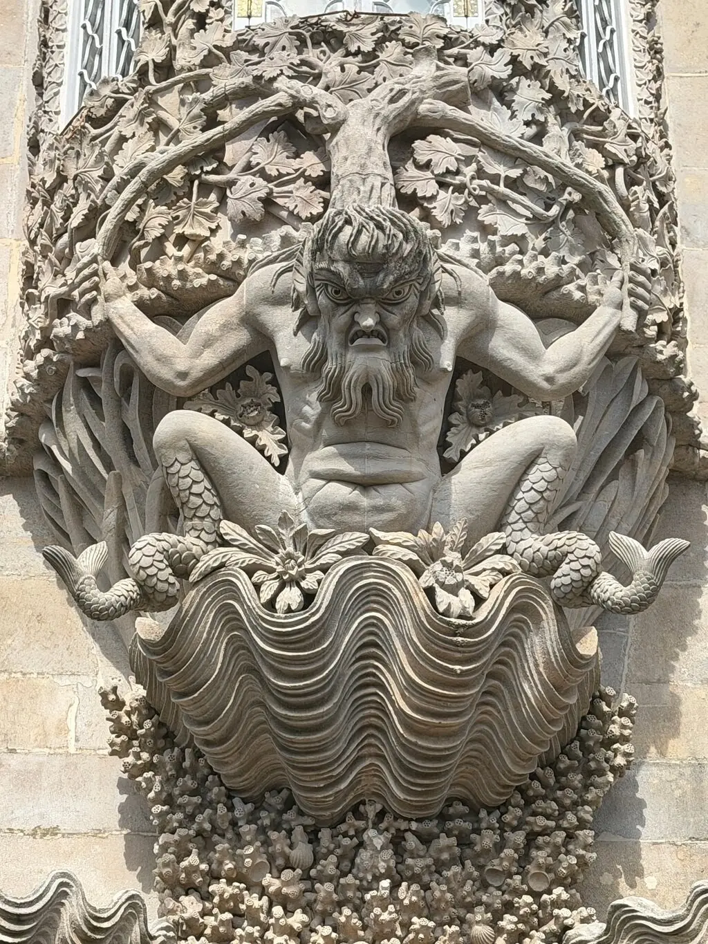 Close-up of the carved Triton figure under a window at the Pena Palace